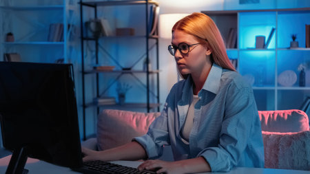 Late work. Female specialist. Internet research. Smart woman typing computer keyboard sitting desk in dark neon light room interior.の写真素材