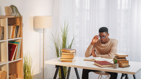 College research. University homework. Concentrated smart young man reading scientific literature book preparing school exam test at home desk copy space.の写真素材