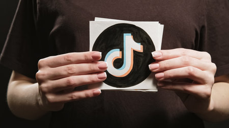 Kharkiv, Ukraine - May 12, 2020: TikTok logo. Social media application. Female hands showing site...