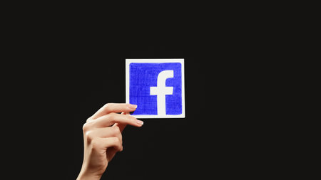Kharkiv, Ukraine - May 12, 2020: Facebook logo. Social network. Digital marketing. Woman hand...