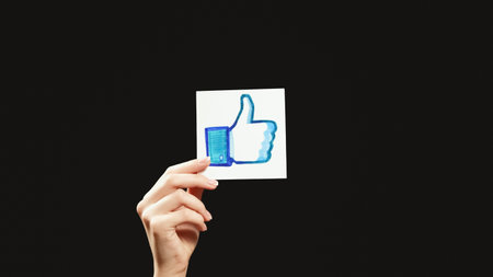Kharkiv, Ukraine - May 12, 2020: Like icon. Follow social network. Female hand showing thumb up design sign isolated on dark black empty space background.のeditorial素材