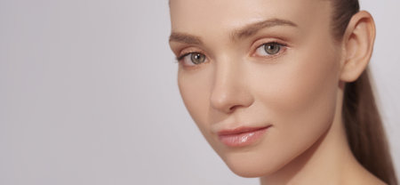 Skincare wellness. Beauty model. Cosmetics advertising. Gorgeous young woman with fresh glowing radiant face skin isolated on grey background empty space.の写真素材