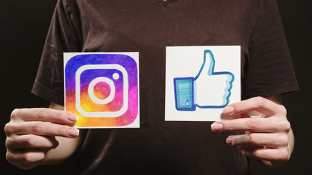 Kharkiv, Ukraine - May 12, 2020: Instagram like. Social media feedback. Female hand showing app icon thumb up design sign on dark free space.のeditorial素材