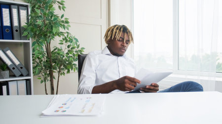 Business analysis. Office documents. Professional man reading project report papers data with graphs charts diagrams sitting at desk at modern workplace.の写真素材