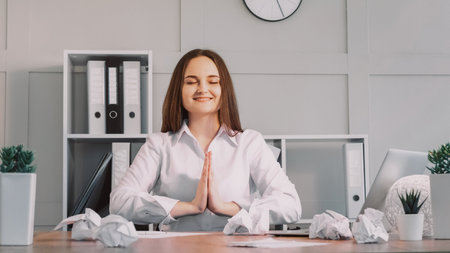 Office yoga. Laptop work. Calm satisfied smiling business woman with praying gesture relaxing at work sitting at desk at workplace.の写真素材
