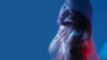 Depressed face. Color light portrait. Double exposure of unhappy unsmiling woman with soul pain isolated on neon blue empty space background.の写真素材