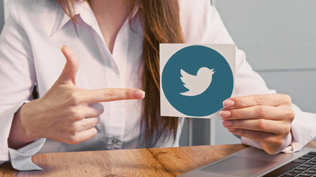 Kharkiv, Ukraine - May 13, 2020: Twitter icon. Social media. Unrecognizable woman pointing finger at internet network logo.のeditorial素材