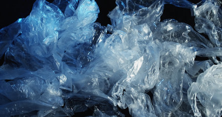 Waste management. Plastic recycling. Used wet empty cellophane polyethylene transparent bags crushed bottles garbage rubbish on dark background.の写真素材
