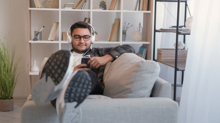 Mobile music enjoying man headphones couch homeの写真素材