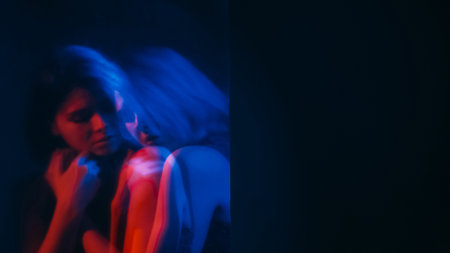 Vulnerable woman. Defocused silhouette. Lonely sad female depression insecure mental covering neon red blue double exposure empty space out of focus.の写真素材