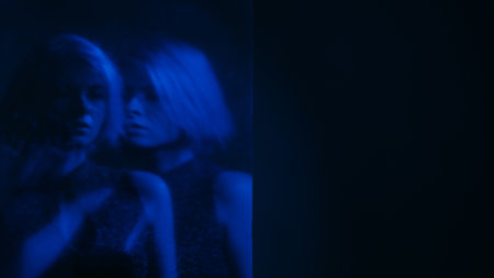 Dual personality. Blur silhouette. Internally suffering sad woman out of focus mental disorder neon blue color double exposure dark free space.の写真素材