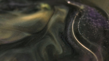 Sparkling liquid. Luxury ink. Defocused black golden color mixing glitter particles spill shimmer...