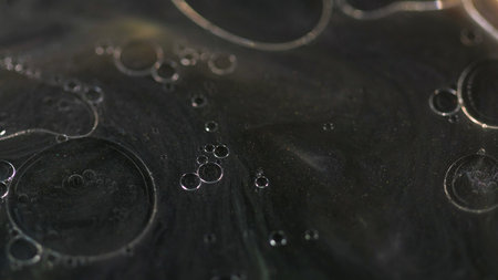 Oil bubbles. Shimmer ink. Defocused black golden color floating translucent drops shiny particles...