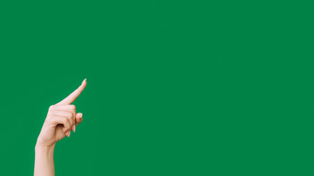 Pointing finger. Advertising background. Sale discount. Female hand showing recommending something invisible isolated on green empty space.の写真素材