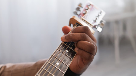 Guitar music. Artist playing. Chord practice. Performer man hand fingers learning jazz song melody on acoustic string instrument fretboard indoors.の写真素材