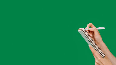 Idea note. List planning. Checklist review. Female hands writing with pen in notepad isolated on green empty space background.の写真素材