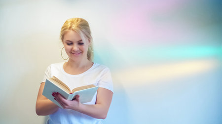 Happy read. Book leisure. Relaxed smart woman enjoying interesting fairytale story literature on pastel rainbow color copy space background.の写真素材