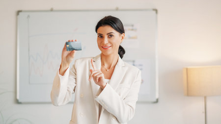 Credit bonus. Female manager. Banking operation. Happy elegant woman showing plastic card staying light office room interior.の写真素材