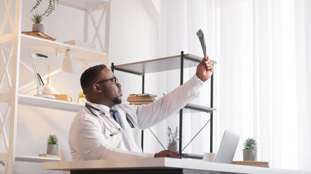 Radiology expertise. Medical diagnosis. Hospital healthcare. Serious man physician doctor examining injury x ray working at laptop at clinic.の写真素材