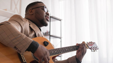 Guitar singing. Music performer. Vocalist artist. Talented creative man playing song on acoustic string instrument at home window free space.の写真素材