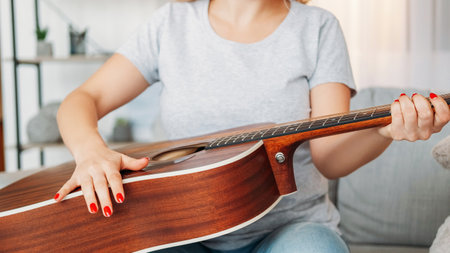 String instrument. Female player. Home lesson. Unrecognizable woman adjusting sound of acoustic...