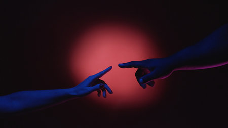 Human solidarity. Ethnic equality. Multicultural diversity. Man and woman hands fingers touching in creative advertisement on red spotlight background.の写真素材