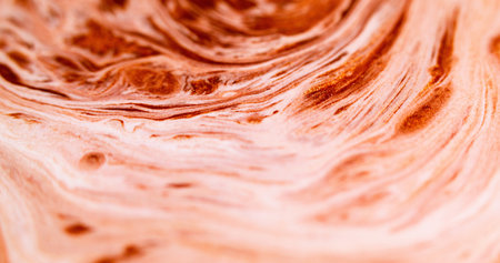 Paint wave. Molten lava. Defocused red white golden color glowing sparkling glitter particles texture ink fluid spreading abstract art background.の写真素材