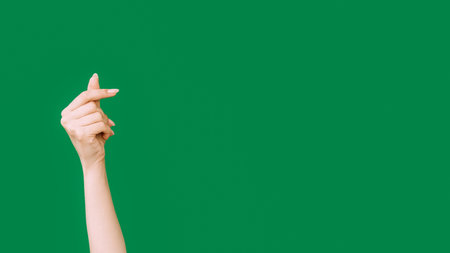 Heart gesture. Like symbol. Charity gratitude. Female hand showing appreciation finger love sign isolated on green empty space background.の写真素材