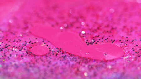 Liquid glitter texture. Shimmer fluid flow. Defocused pink color sparkling sequin particles gloss gel ink paint emulsion floating abstract art background.の写真素材