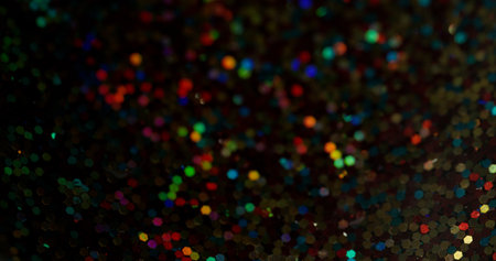 Defocused confetti flicker. Sparkling glitter. Multicolor yellow green red purple blurry round gleaming blinking lens flare on bokeh light background.の写真素材