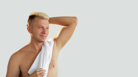 Man freshness. Morning routine. Confident shirtless blond guy with athletic body towel on bare shoulder touching short hair after shower isolated on neutral empty space background.の写真素材