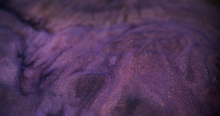 Blurred ink spill. Glitter fluid mix. Defocused purple color glowing sparkling marble texture acrylic wave on dark abstract art background.の写真素材