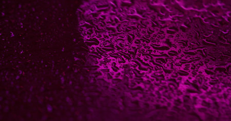 Condensate texture. Water droplets. Sparkling colorful purple fluid rain gleaming blinking liquid on abstract bokeh light background.の写真素材