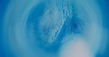 Shimmering flow. Blur spill. White blue color fluid blinking liquid paint ink bright dust circling on abstract bokeh light background.の写真素材