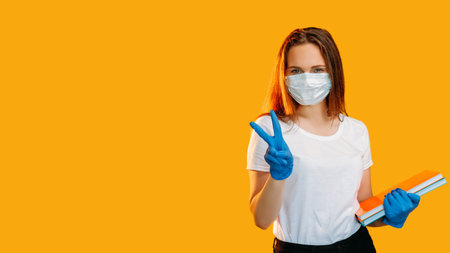 Quarantine education. School reopen. Cheerful female student in protective face mask gloves showing...