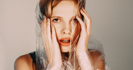 Anxiety attack. Defocused art portrait of disturbed beautiful woman in polyethylene film hood...