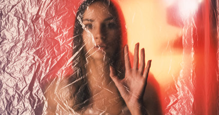 Female freedom. Beauty girl. Defocused woman fading in wrinkled texture film on red orange glow out of focus copy space background.の写真素材