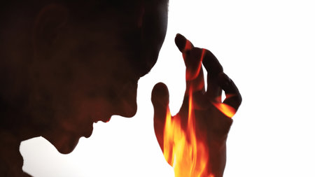 Emotional burnout. Disturbed silhouette. Pain pressure. Dark contrast double exposure profile outline of suffering woman in fire flames isolated on white copy space background.の写真素材