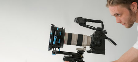 Videographer work. Studio cameraman. Man looks into lens professional camera. Male operator directs...