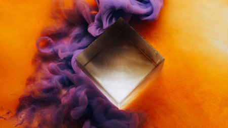 Mist blow. Magic cloud. Color smoke wave spill near glass cube. Violet vapor paint haze flow on vivid blur orange background.の写真素材