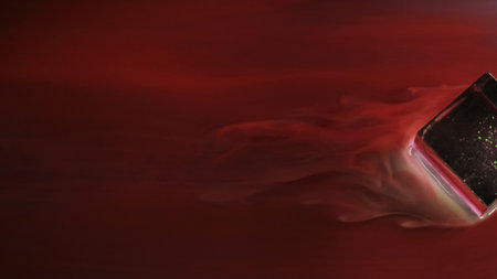 Red flow. Marbling stream. Liquid paint with smoky silky texture washes glass cube. Colored winding stream with blurred water abstract background.の写真素材