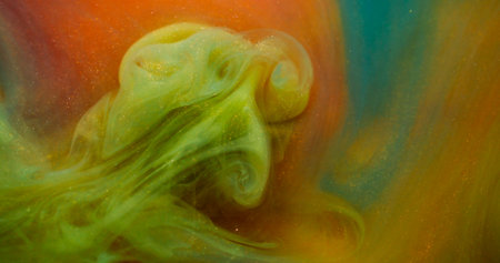 Glitter water. Flow particles. Defocused yellow blue orange color sparkling ink substance on...