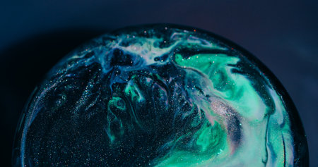 Wet shimmering. Acrylic spill. Black green sparkling paint mixing abstract color circle. Pigment texture defocused background.の写真素材