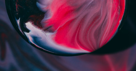 Art liquid. Blur glitter paint. Red blue black emulsion blend in round lens. Swirl flow spilling on defocused color abstract background.の写真素材