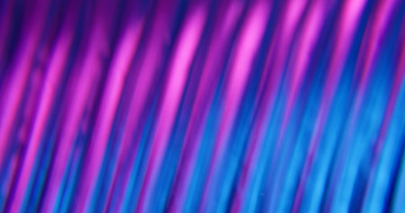 Blur light glow. Glitter abstraction. Defocused purple blue fluorescent visual neon lens flare optical moving on dark black illuminated background.の写真素材
