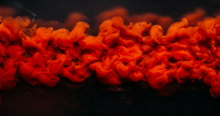 Ink cloud. Shimmer background. Defocused bright red color swirling vapor fume liquid floating on dark black acrylic creative abstraction.の写真素材