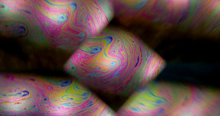 Soap defocused refraction. Kaleidoscope flow. Rainbow iridescent color paint oil diamond shape purple swirl black background night luminosity.の写真素材