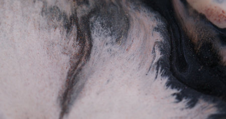 Spatter texture. Spreading ink particles. Defocused orange white color wet drip shiny liquid floating on dark black art background.の写真素材