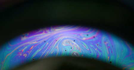 Soap bubble. Neon arch. Colorful round lens paint mix light flow on black background. Purple blue green night defocused abstract overlay.の写真素材