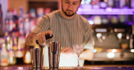 Cocktail making. Bartender mixing. Man spraying pink flavor to drink in metal shaker. Professional...